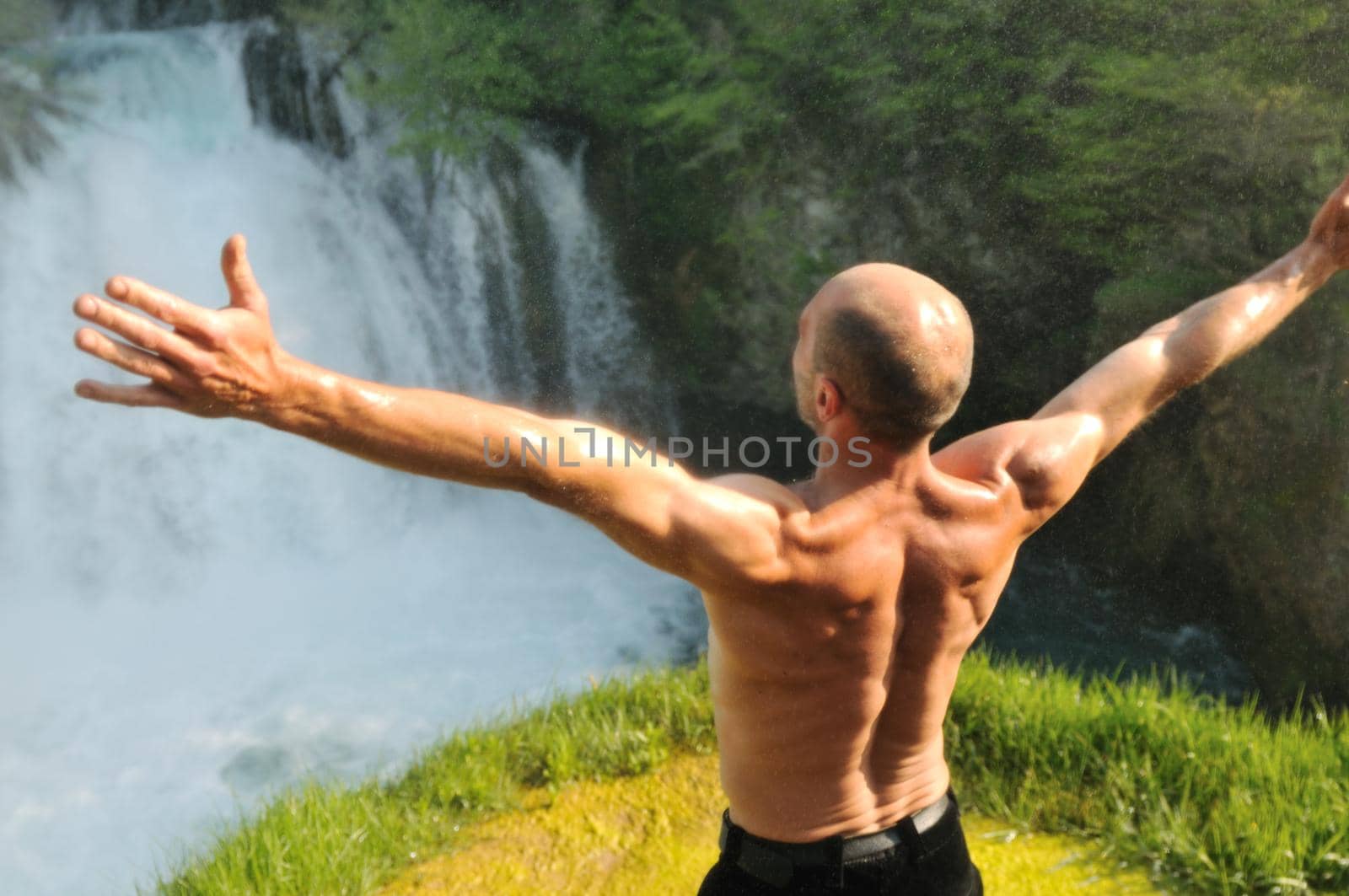 standing man with wide opened arms with waterfalls in background and representing freshness healthy lifestyle and success concept