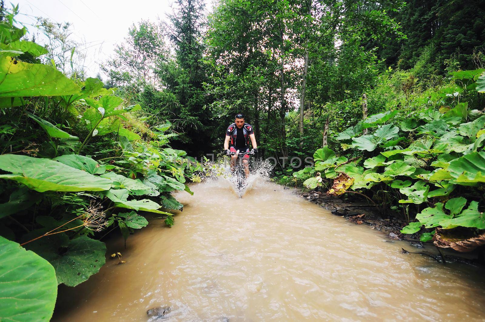 young man drive mountain bike over water river