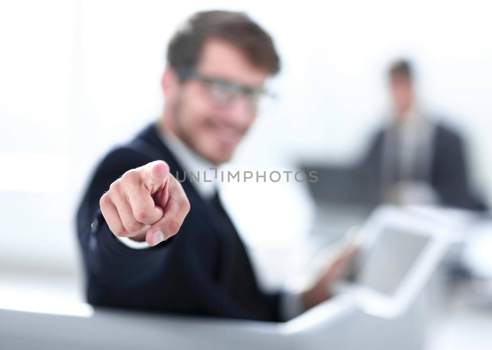 a young business man points a finger at the camera, in his hand holds a tablet