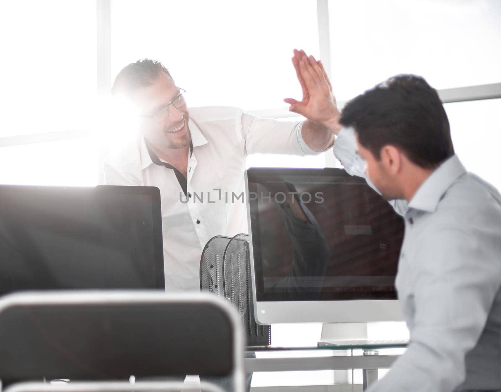 employees give each other a high five over the computer Desk by asdf