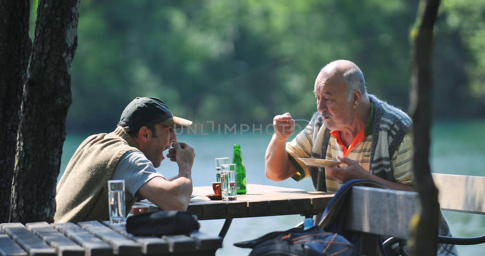 happy family concept with elderly father and son at outdoor restaurant eating tasty dessert