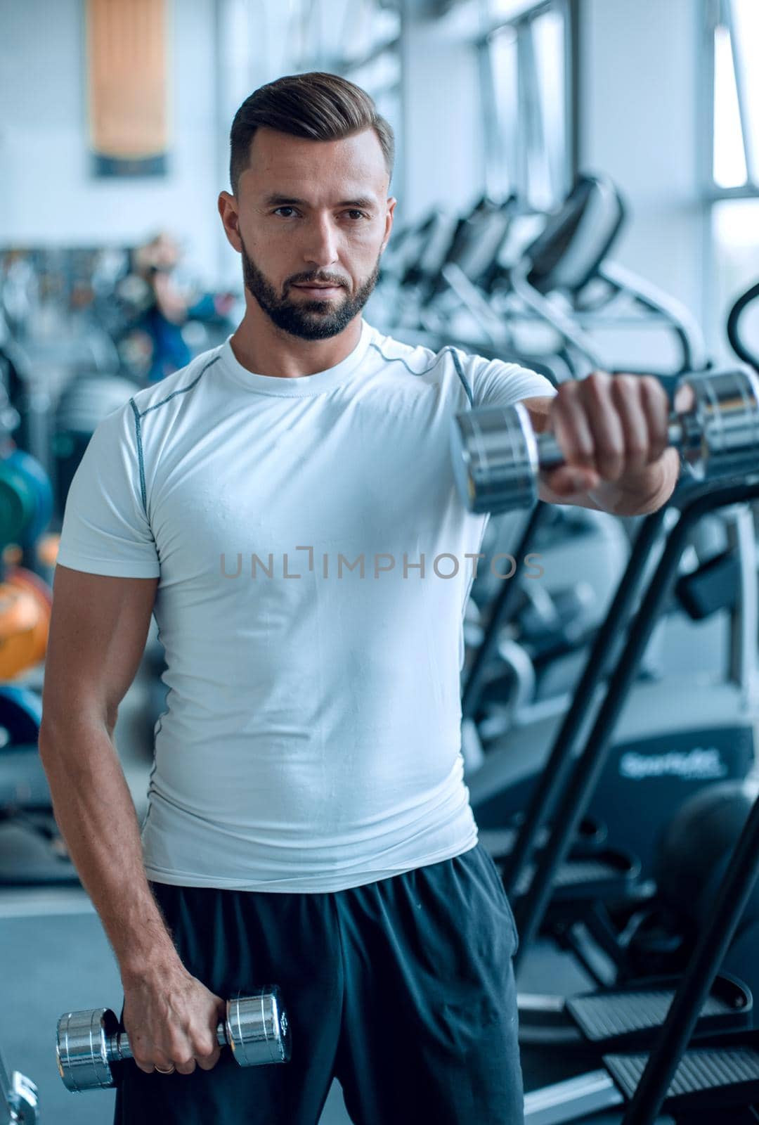 close up.an attractive man works with dumbbells in the gym by asdf