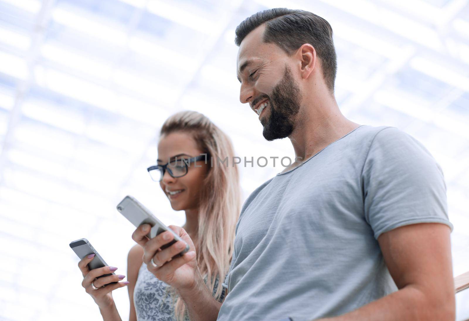 young couple with smartphone on a light background. by asdf