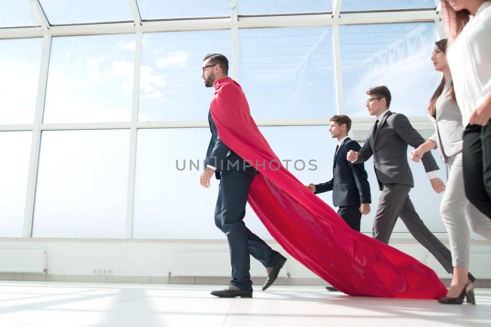 side view.businessman superhero goes ahead of his business team.photo with copy space