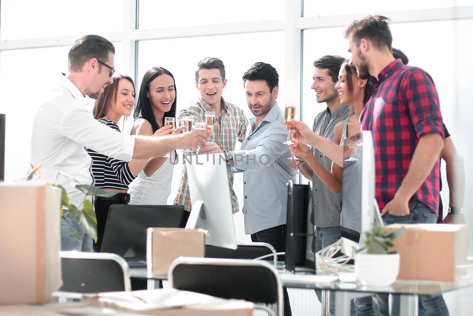 business team raising wine glasses while standing in the office.the concept of a startup