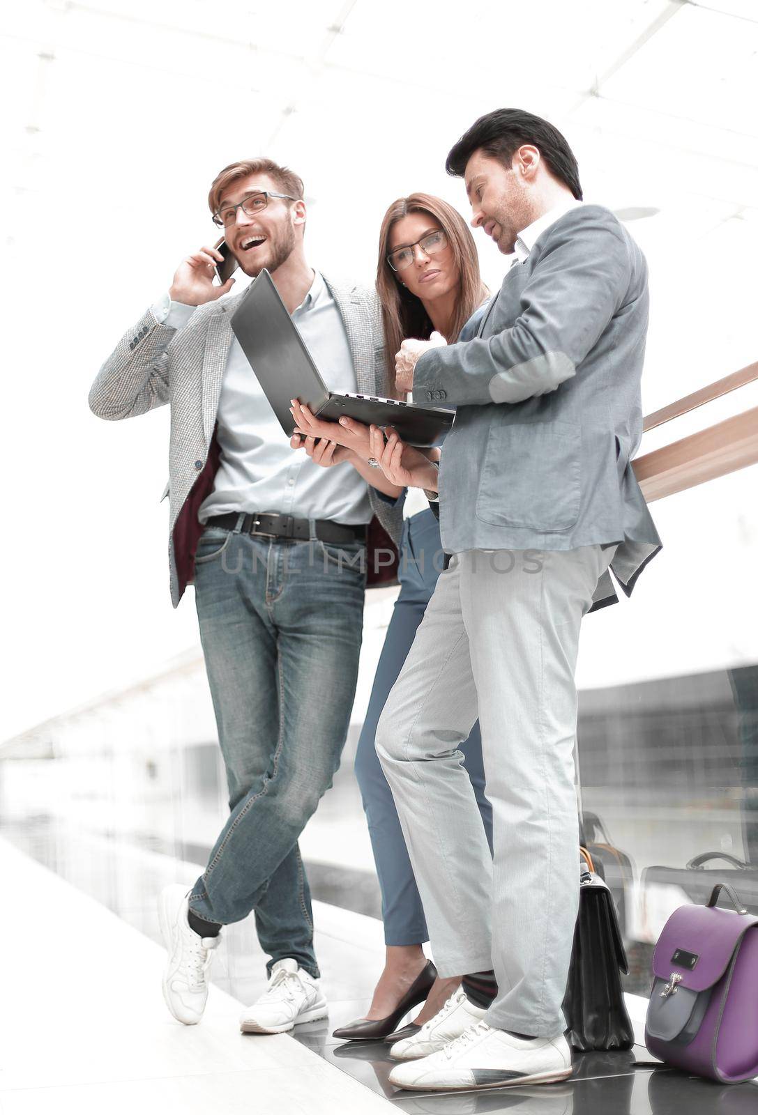 business colleagues using their gadgets standing in the office lobby by asdf