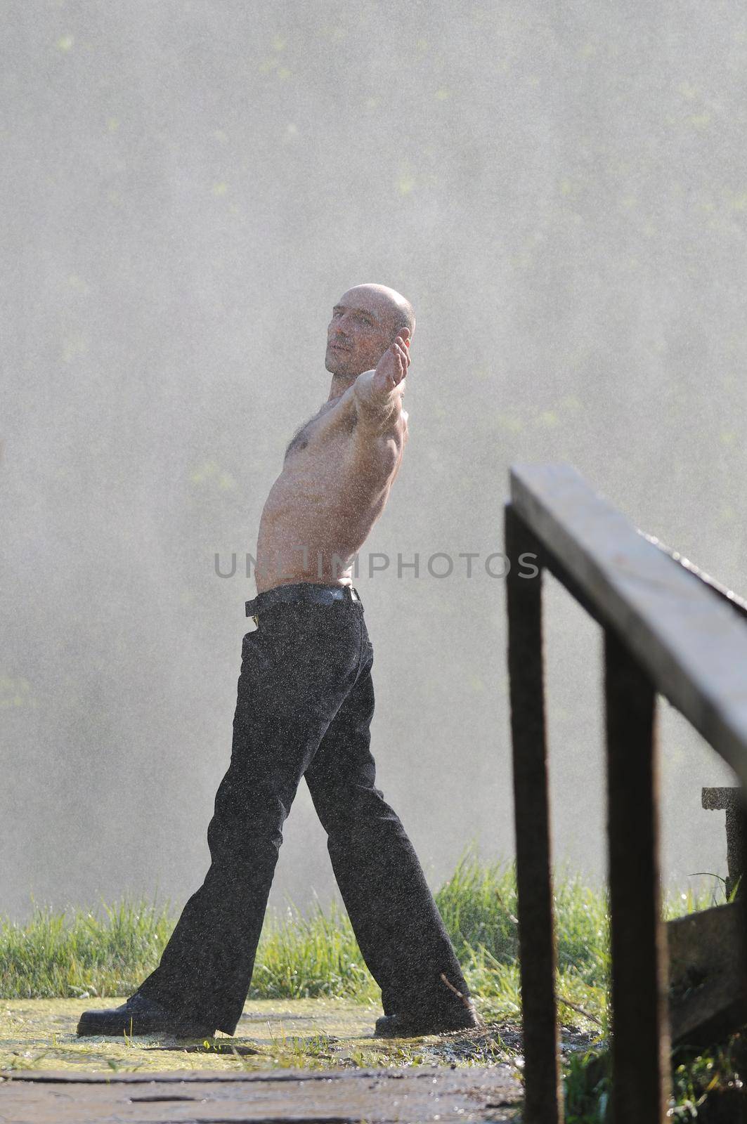 standing man with wide opened arms with waterfalls in background and representing freshness healthy lifestyle and success concept