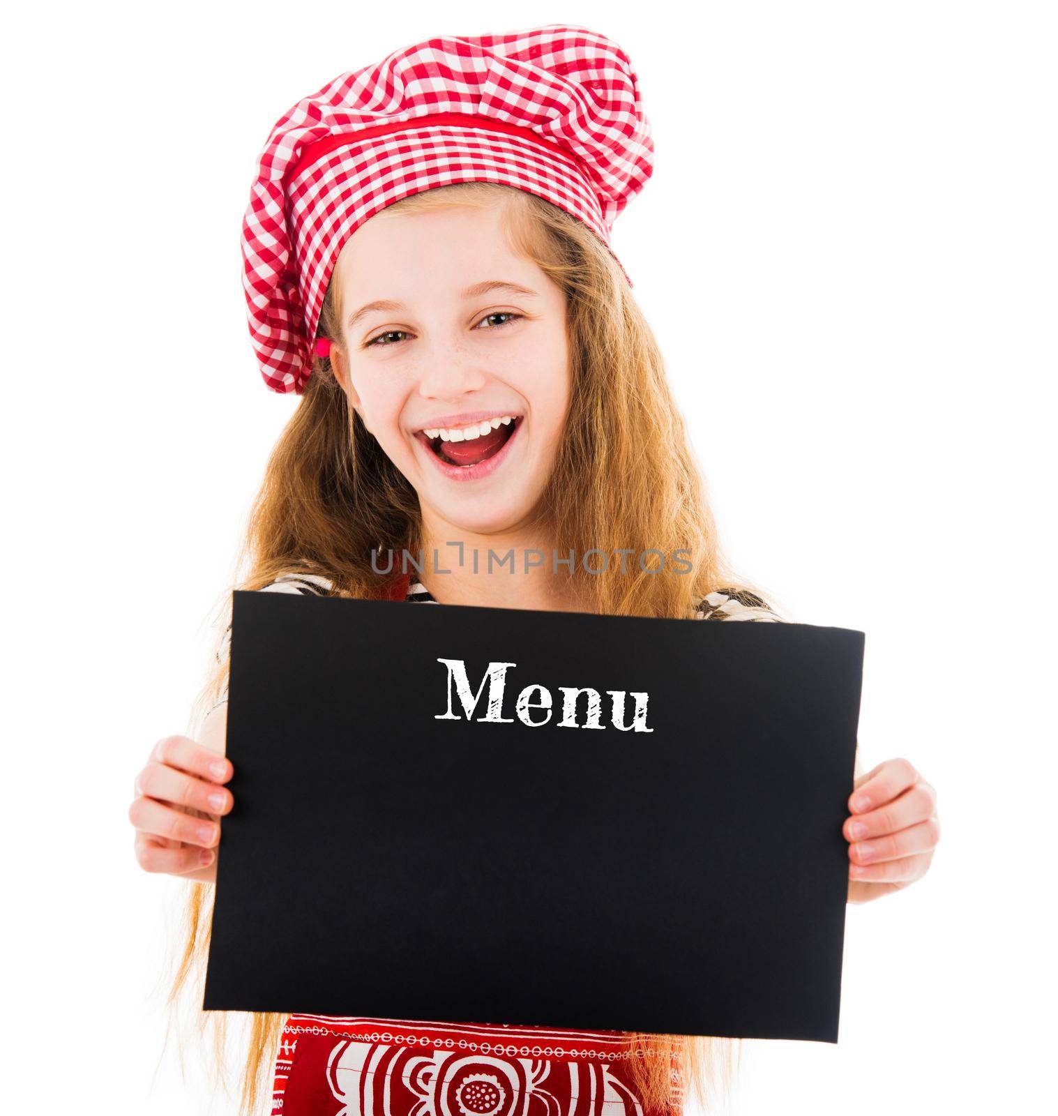 Little girl in kitchen uniform holding menu mockup with copy space in hands and smiling at camera isolated on white background