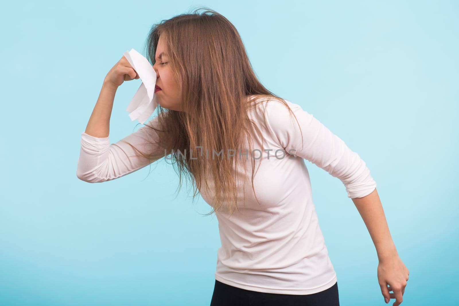 Young man has a runny nose on blue background.