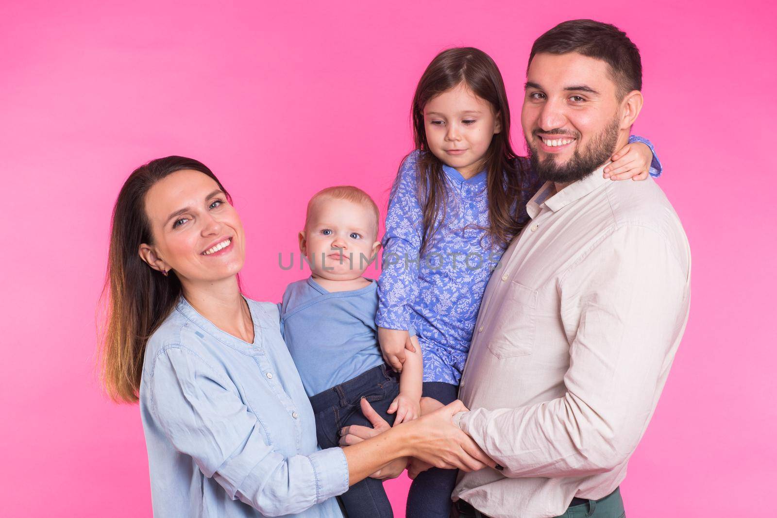 Happy family portrait smiling on pink background.