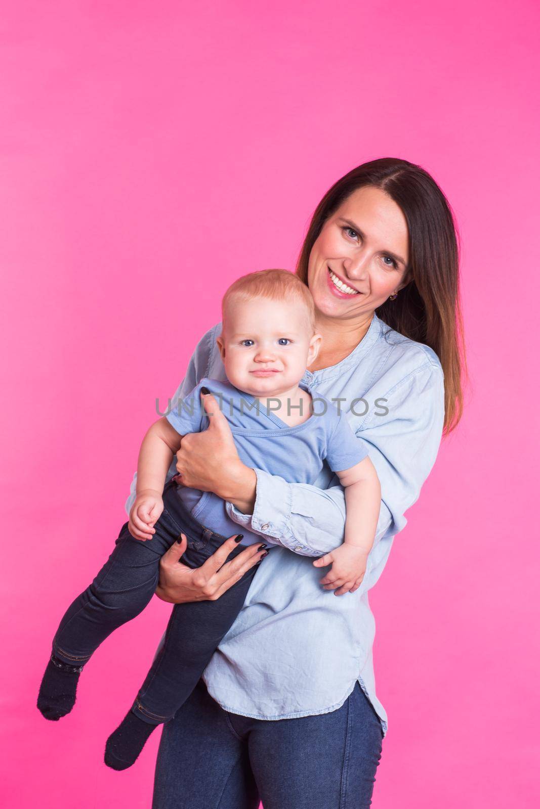 family, motherhood, parenting, people and child care concept - happy mother holds adorable baby over pink background by Satura86