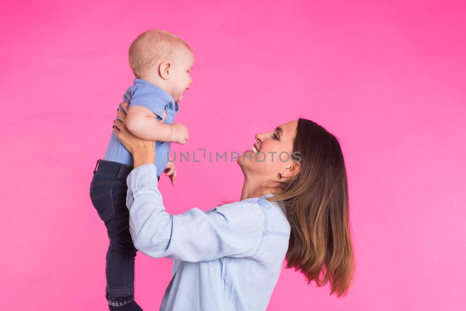 happy young mother with a baby child on pink background.