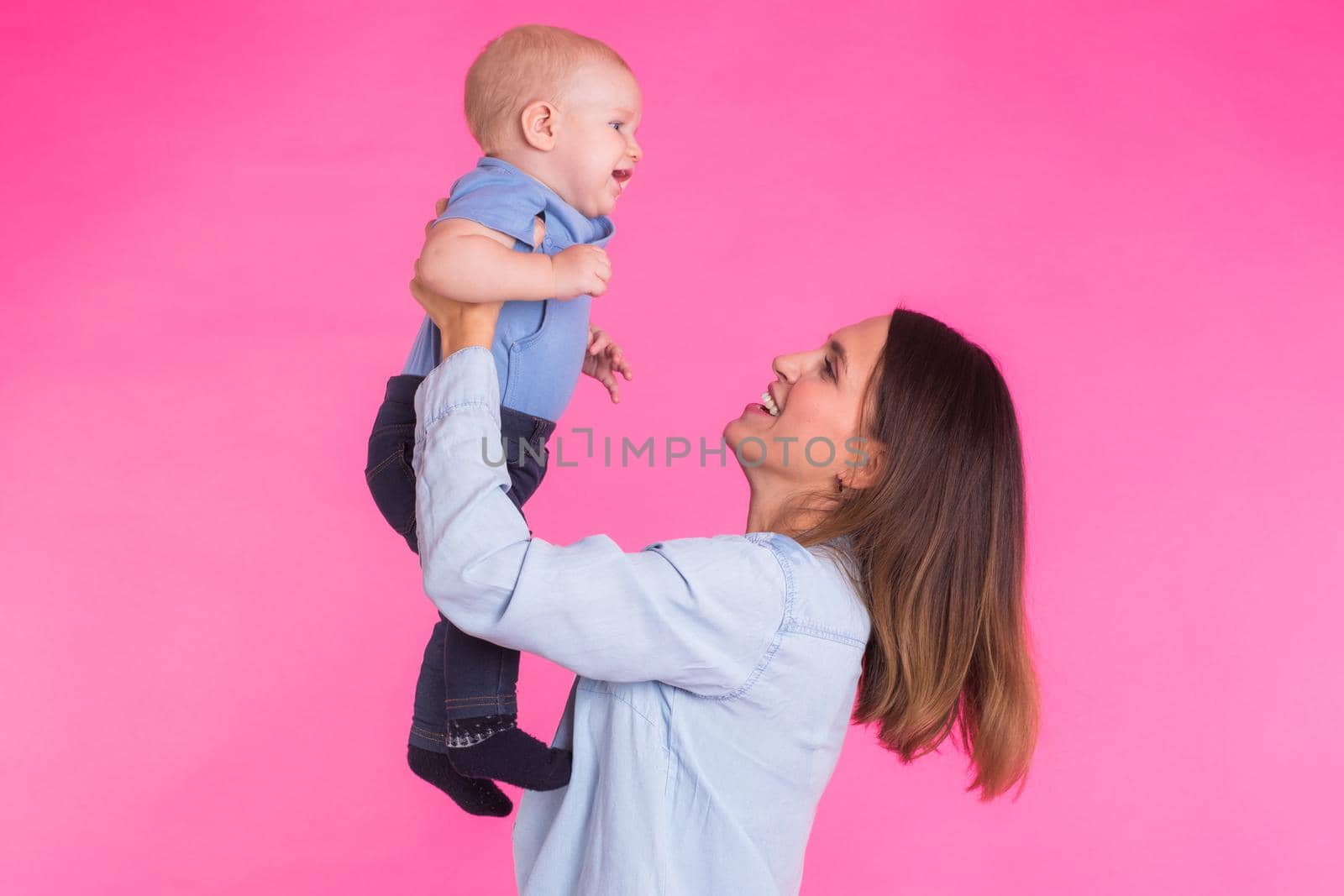 happy young mother with a baby child on pink background.