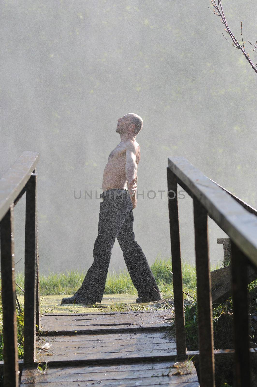 standing man with wide opened arms with waterfalls in background and representing freshness healthy lifestyle and success concept