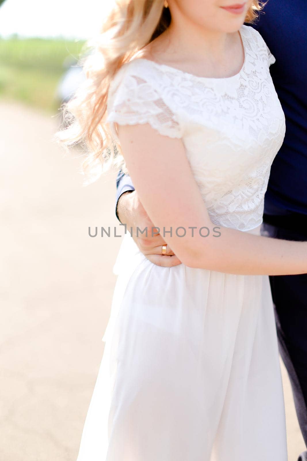 Groom hugging bride and walking on road. Concept of married couple and love.