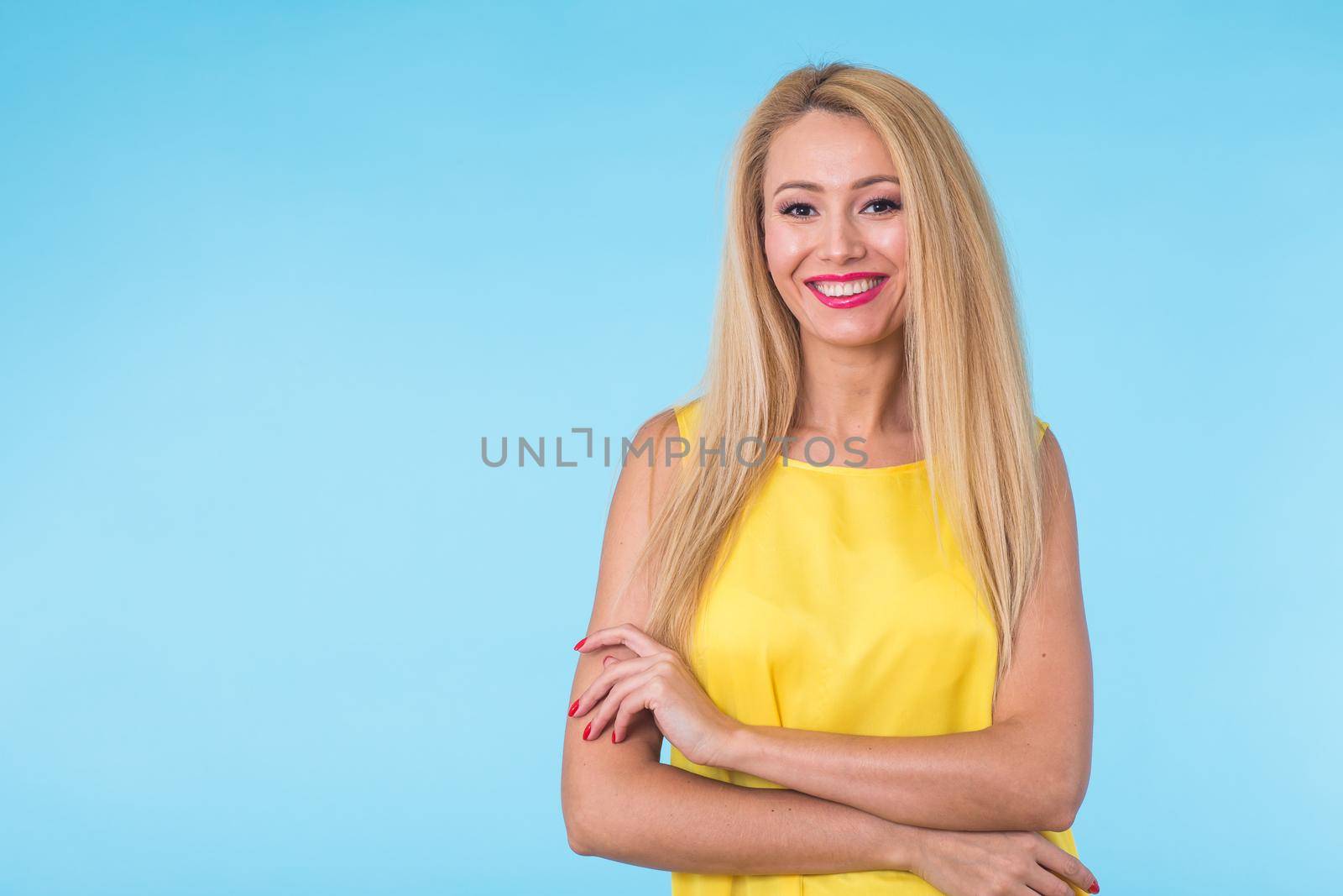beauty fashion summer portrait of blonde woman with red lips and yellow dress on blue background with copy space.