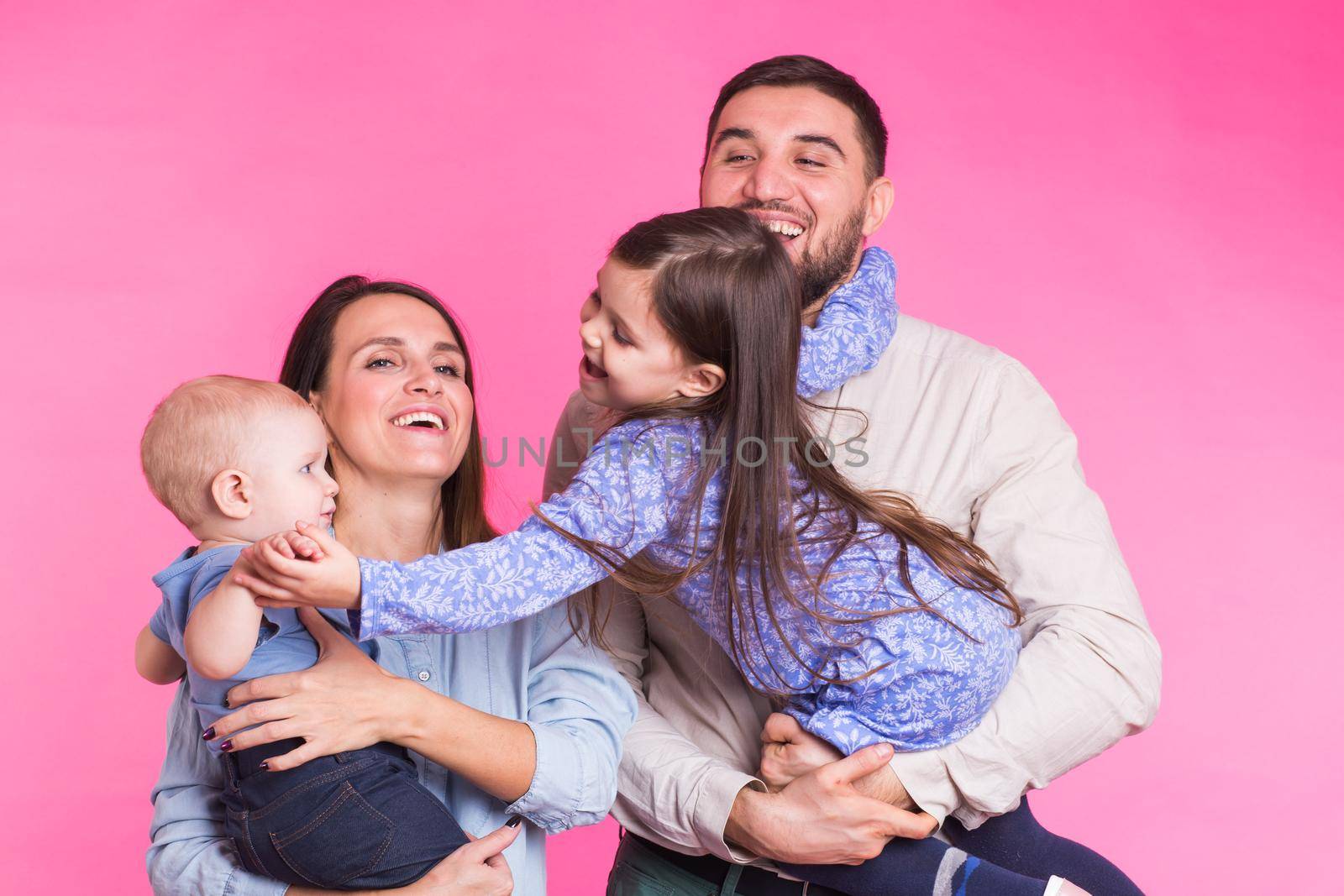 Happy family portrait smiling on pink background.