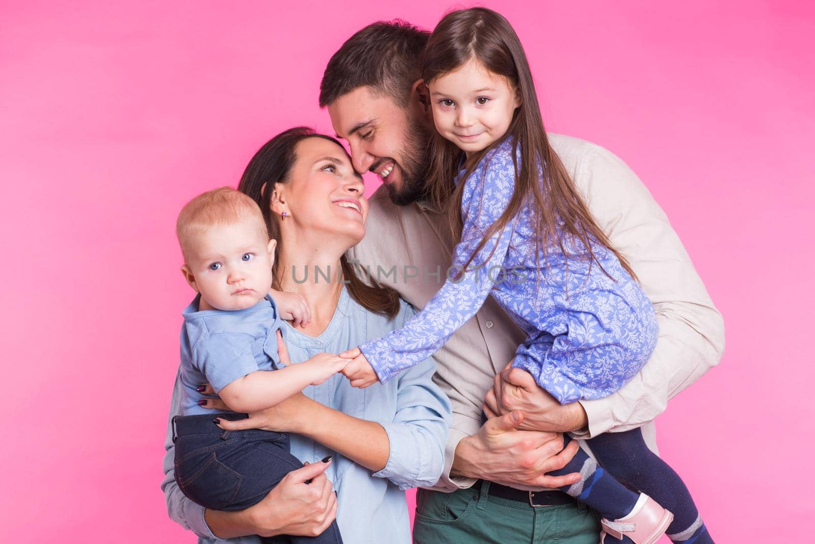 Happy family portrait smiling on pink background.