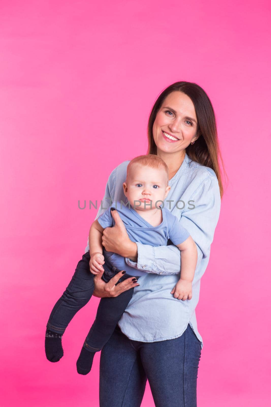 Loving mother playing with her baby boy on pink background by Satura86