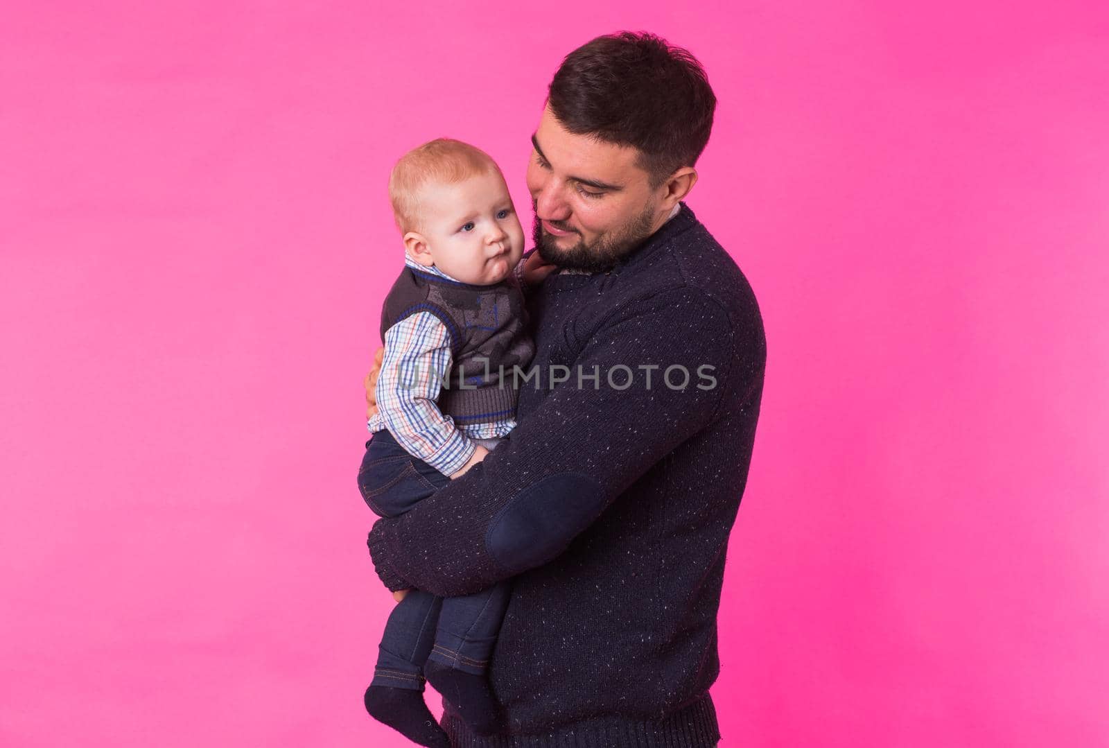 happy father with a baby son isolated on a pink background.