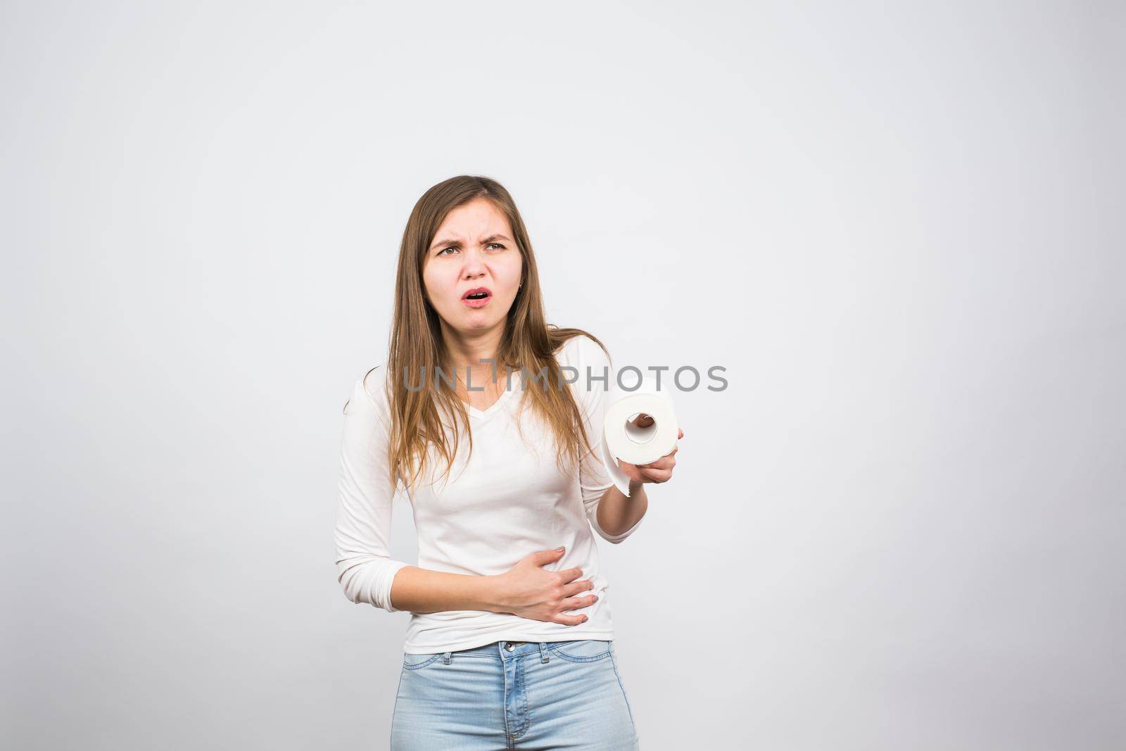 Sick woman with hands pressing her crotch lower abdomen, holding paper roll. Medical problems, incontinence, health care concept.