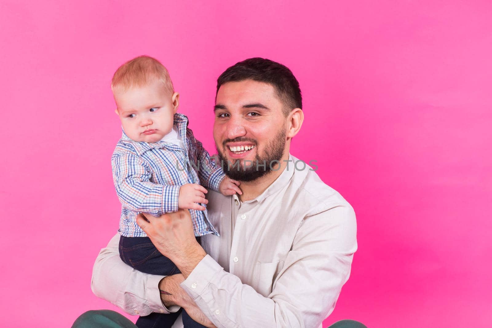 happy father with a baby son isolated on a pink background.