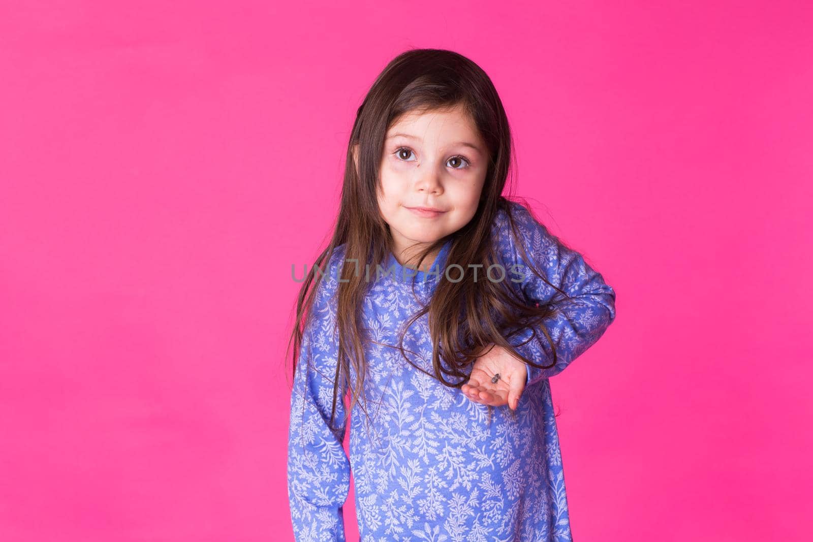 Portrait of adorable little girl isolated on a pink background.