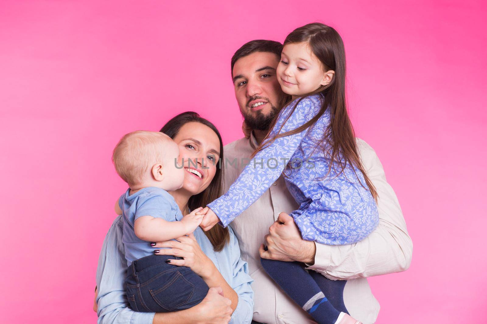 Portrait of Young Happy Mixed Race Family over pink background.