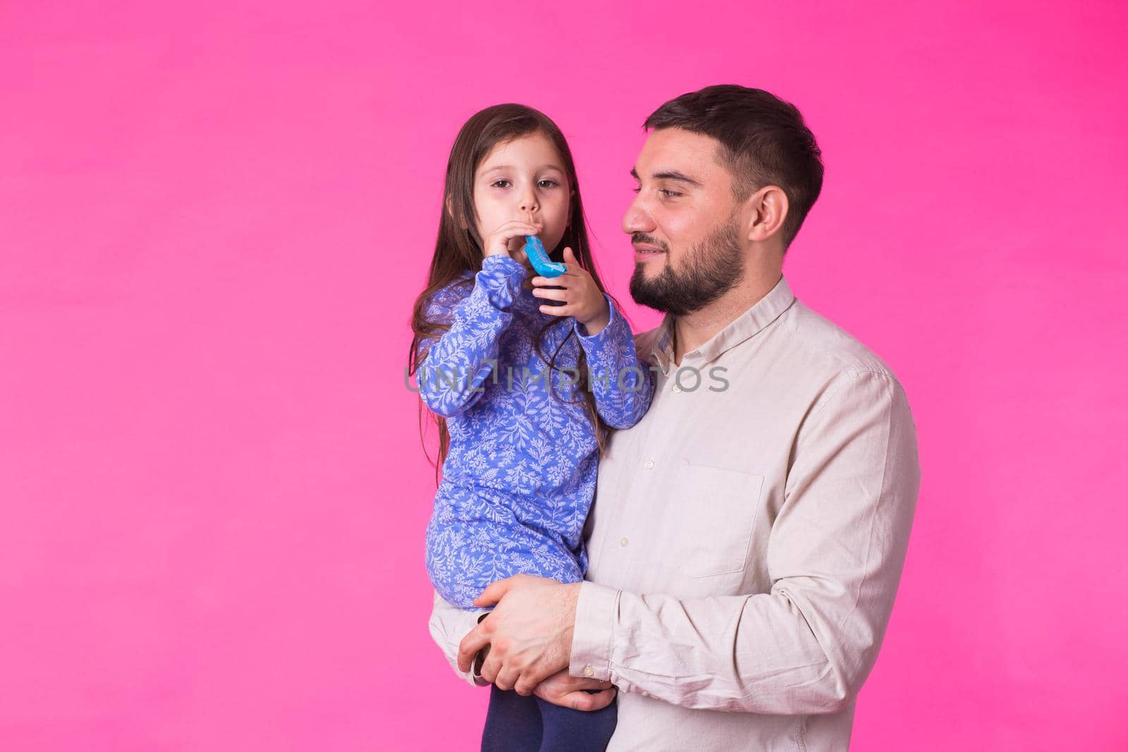 Happy father with his baby daughter on pink background.