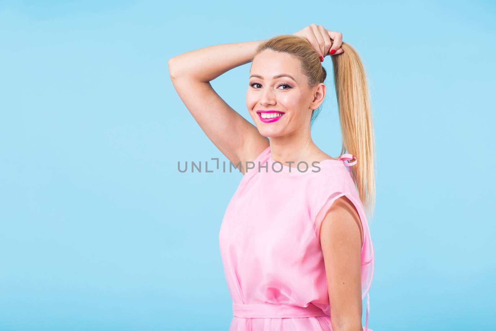 Portrait of happy cheerful smiling young beautiful blond woman on blue background.