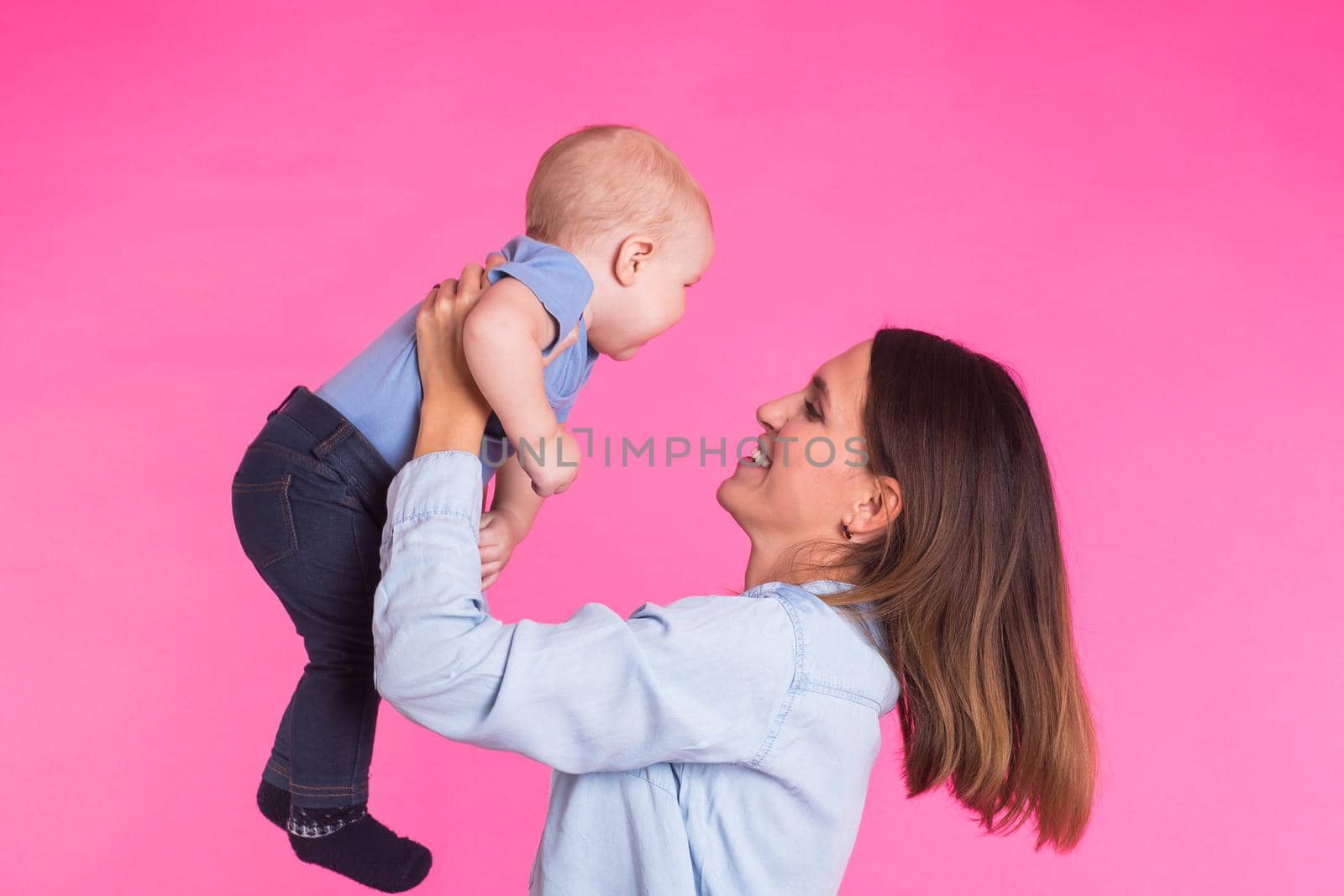 happy young mother with a baby child on pink background by Satura86