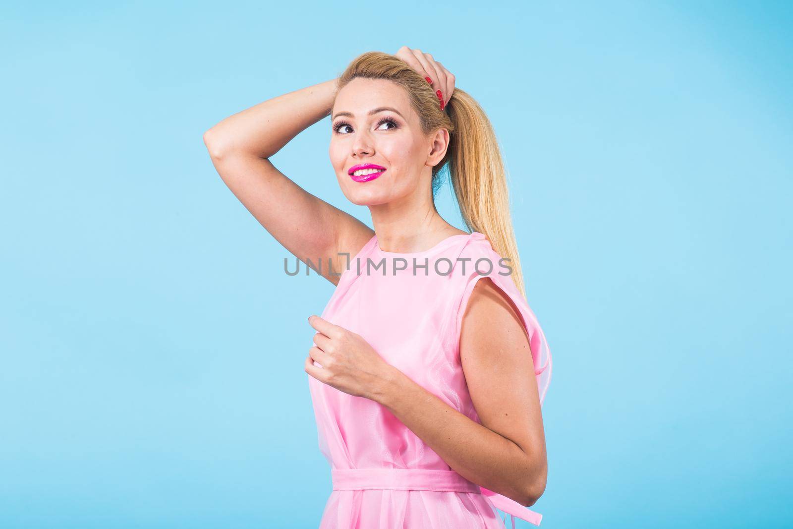 Beautiful woman with long straight blond hair. Fashion model posing at studio on blue background by Satura86