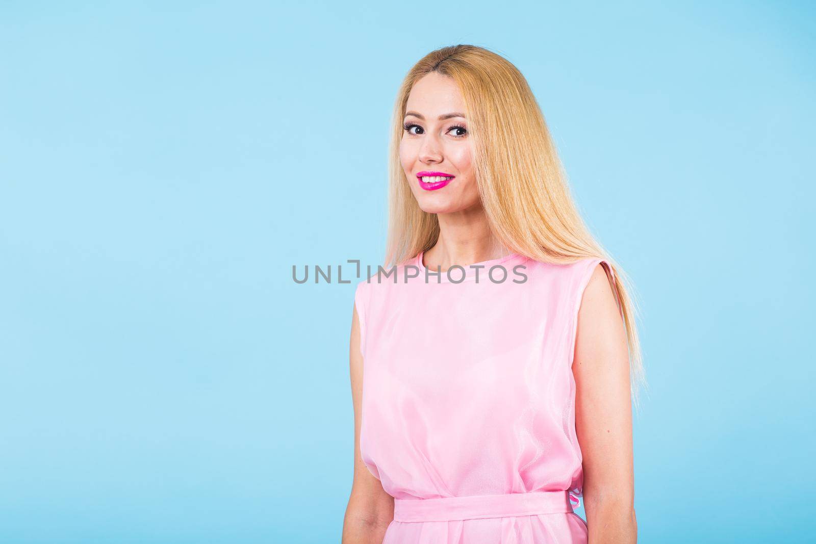 Beautiful woman with long straight blond hair. Fashion model posing at studio on blue background with copyspace by Satura86