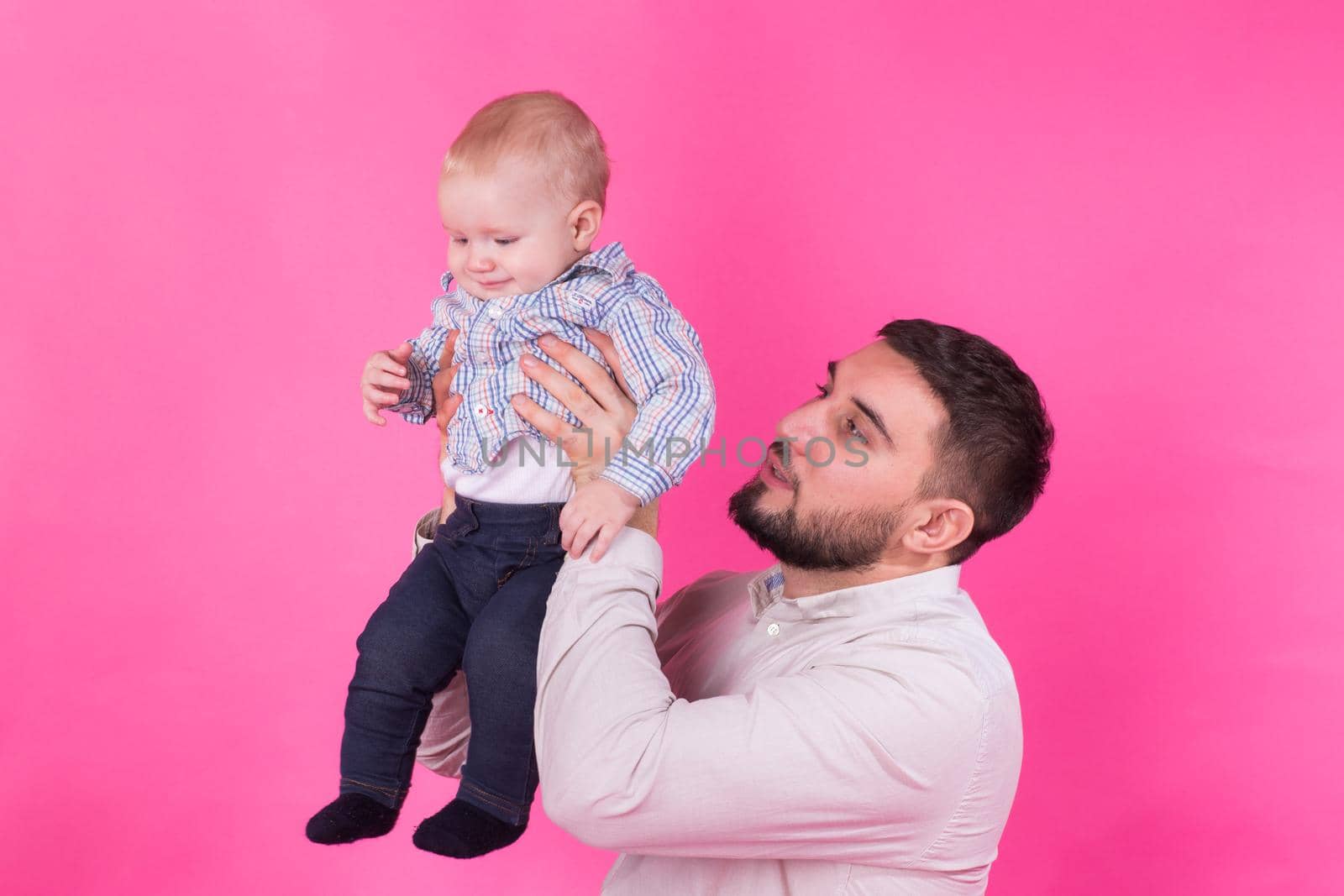 happy father with a baby son isolated on a pink background by Satura86