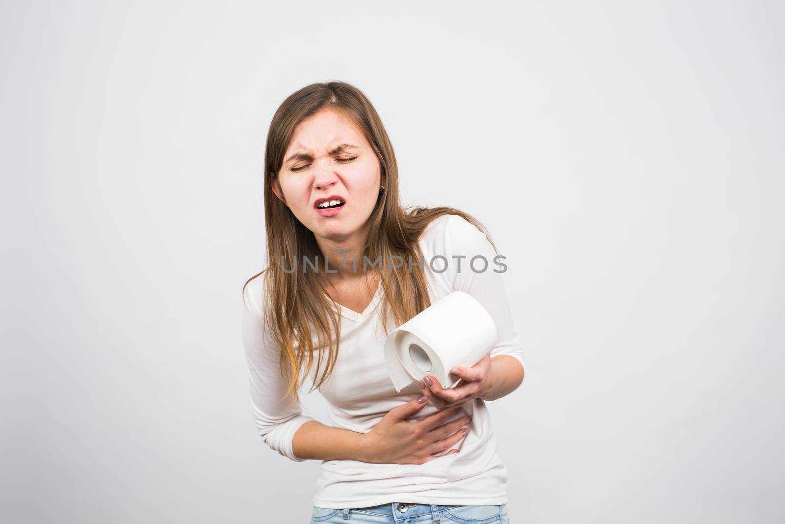 Sick woman with hands pressing her crotch lower abdomen, holding paper roll. Medical problems, incontinence, health care concept.