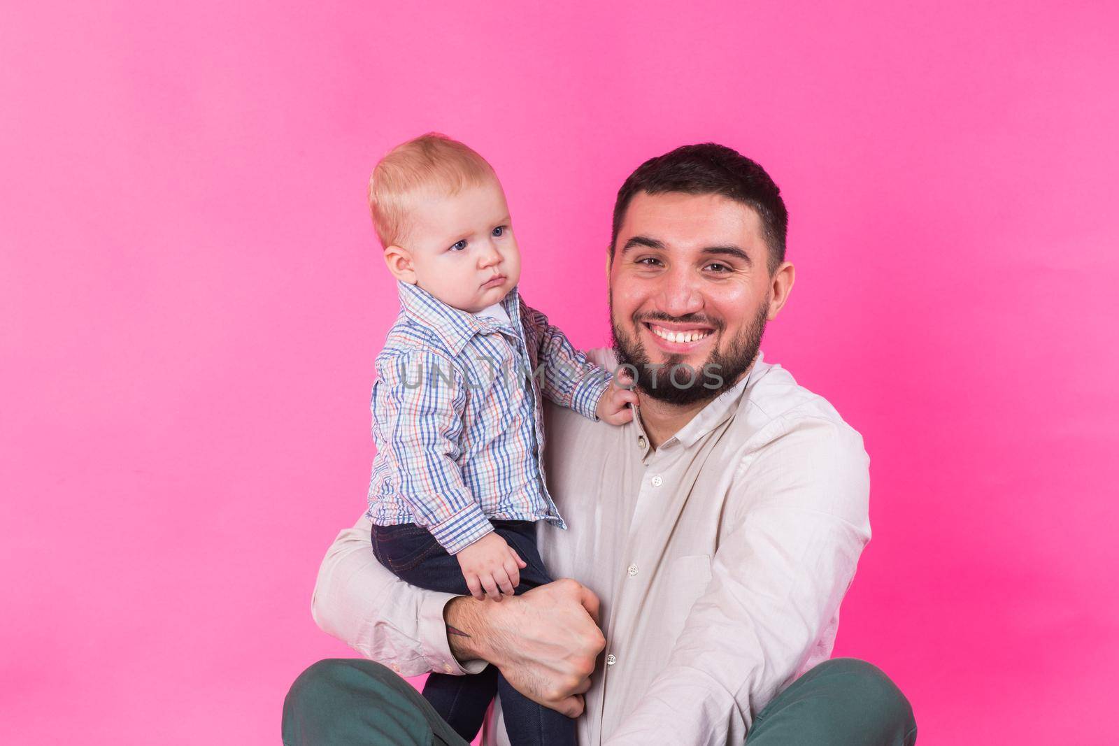 Baby in the daddy hands. Pink background