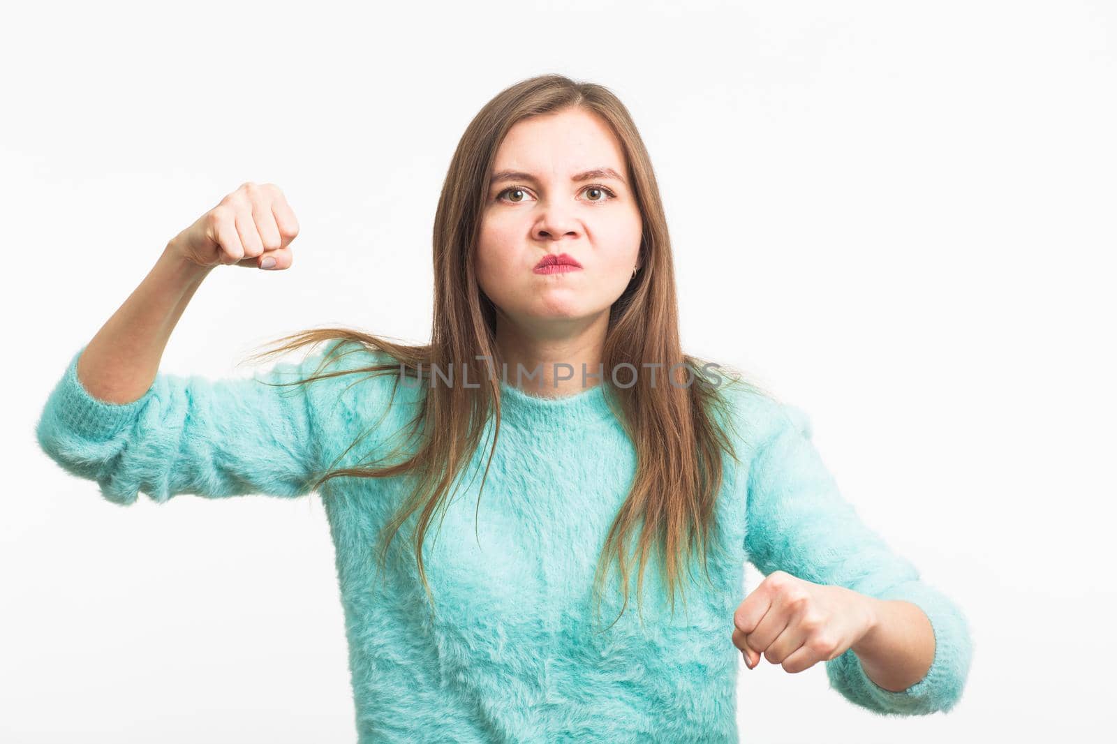 furious young brunette woman shows fist. The girl is very angry and ready to use his fists. Negative aggressive emotions on her face. by Satura86
