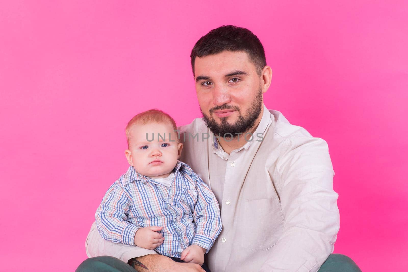happy father with a baby son isolated on a pink background by Satura86