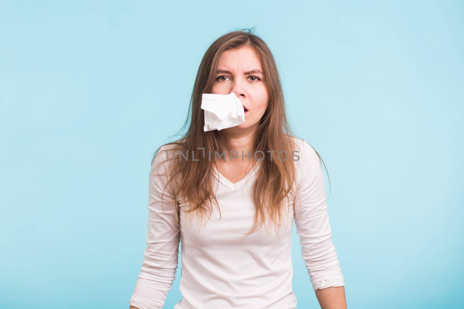 Young woman with handkerchief. Sick girl isolated has runny nose on blue background by Satura86