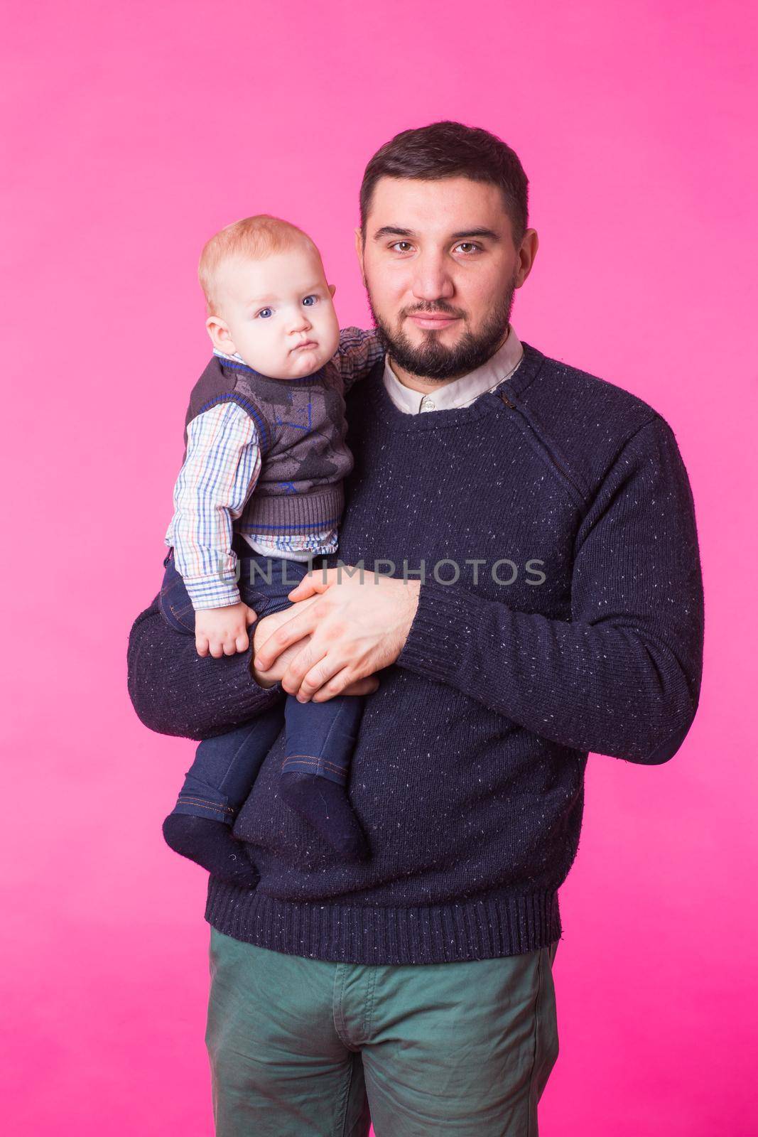 Happy father holding baby son in hands over pink background by Satura86