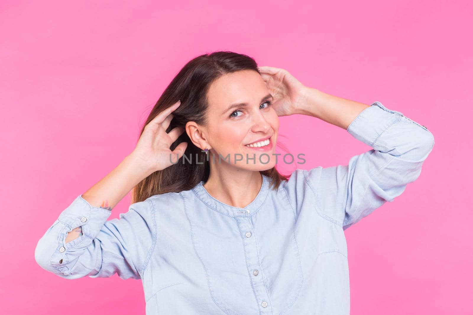 Smiling Woman in shirt posing in studio on pink background.