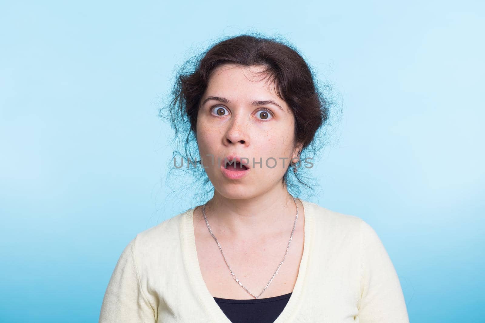 shocked young woman, isolated against blue studio background by Satura86