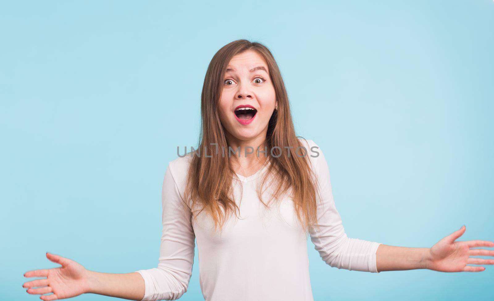 Surprised young woman shouting over blue background. Looking at camera by Satura86