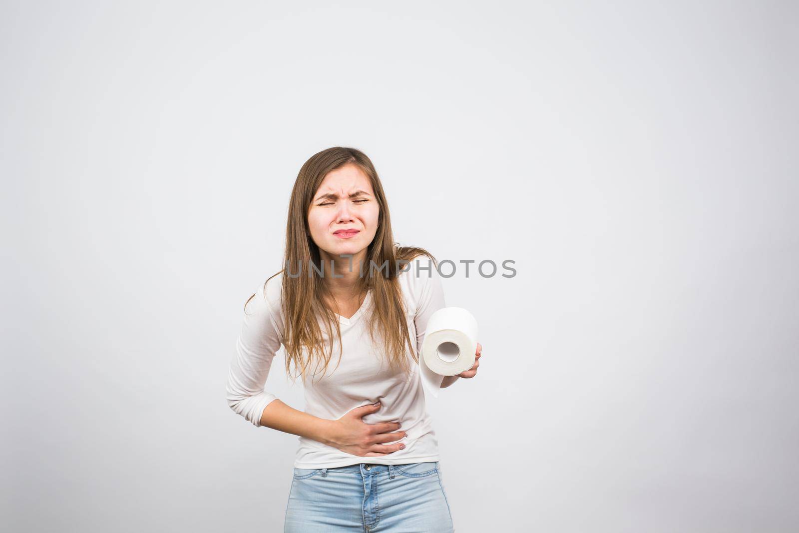 Sick woman with hands pressing her crotch lower abdomen, holding paper roll. Medical problems, incontinence, health care concept.