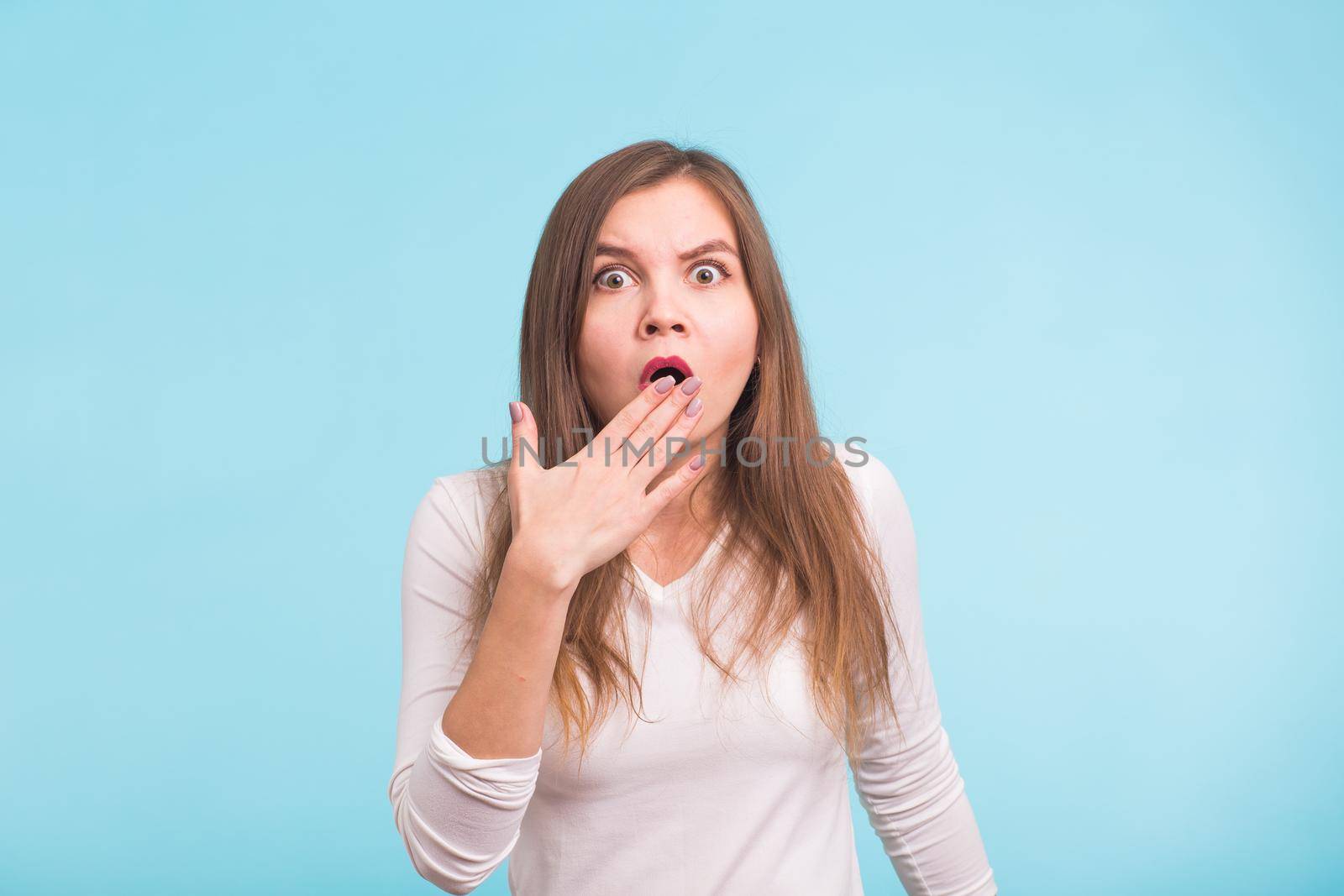 Concerned scared woman on blue background in studio