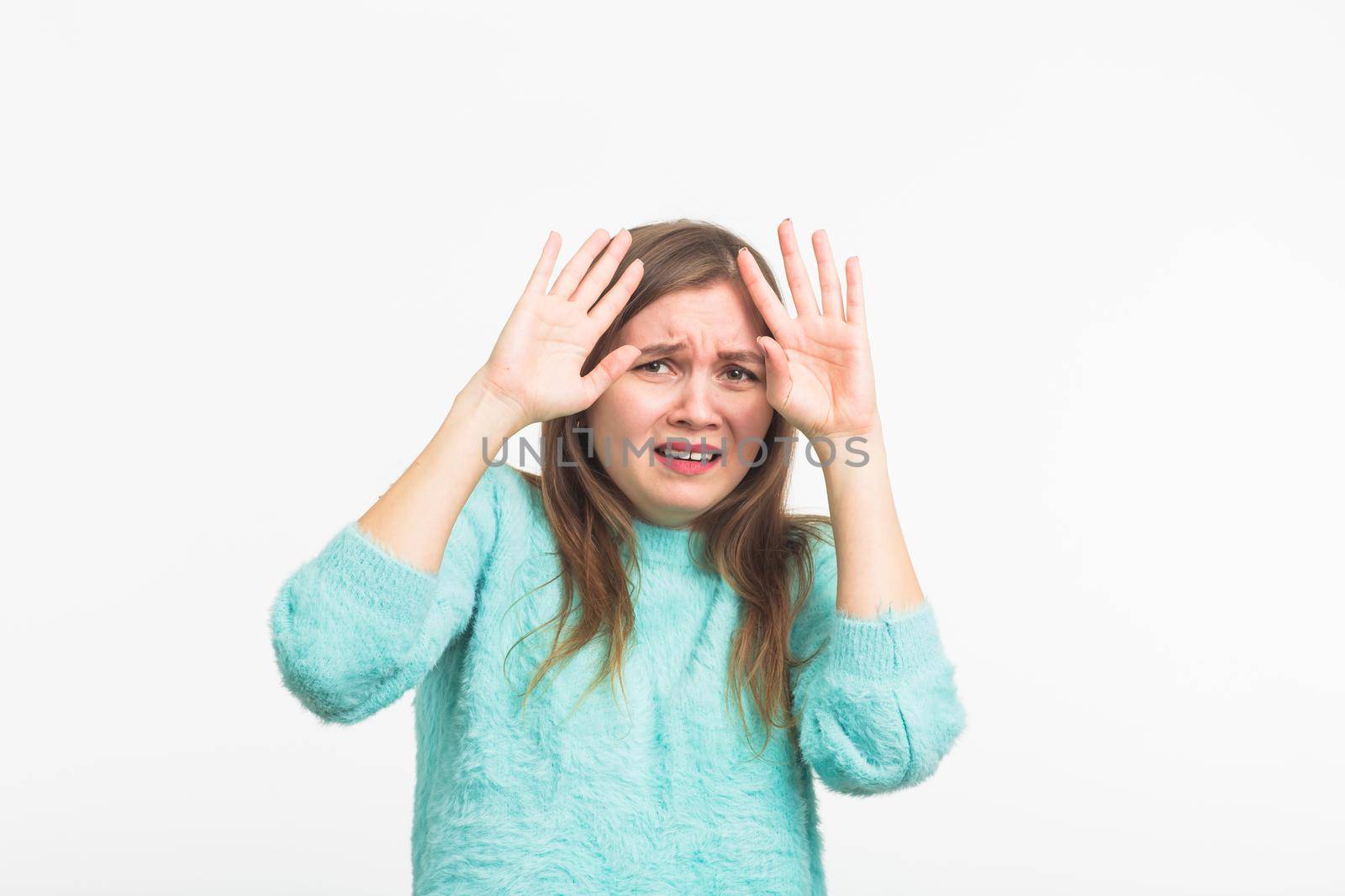 Scared stressful woman with bugged eyes looking terrified into camera. Fearful beautiful young female in casual clothes having bad reaction on horror news .