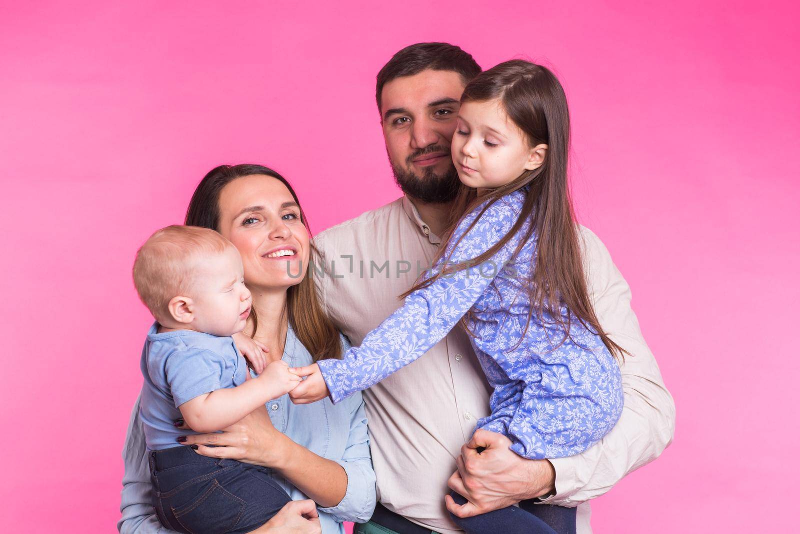 Portrait of Young Happy Mixed Race Family over pink background.