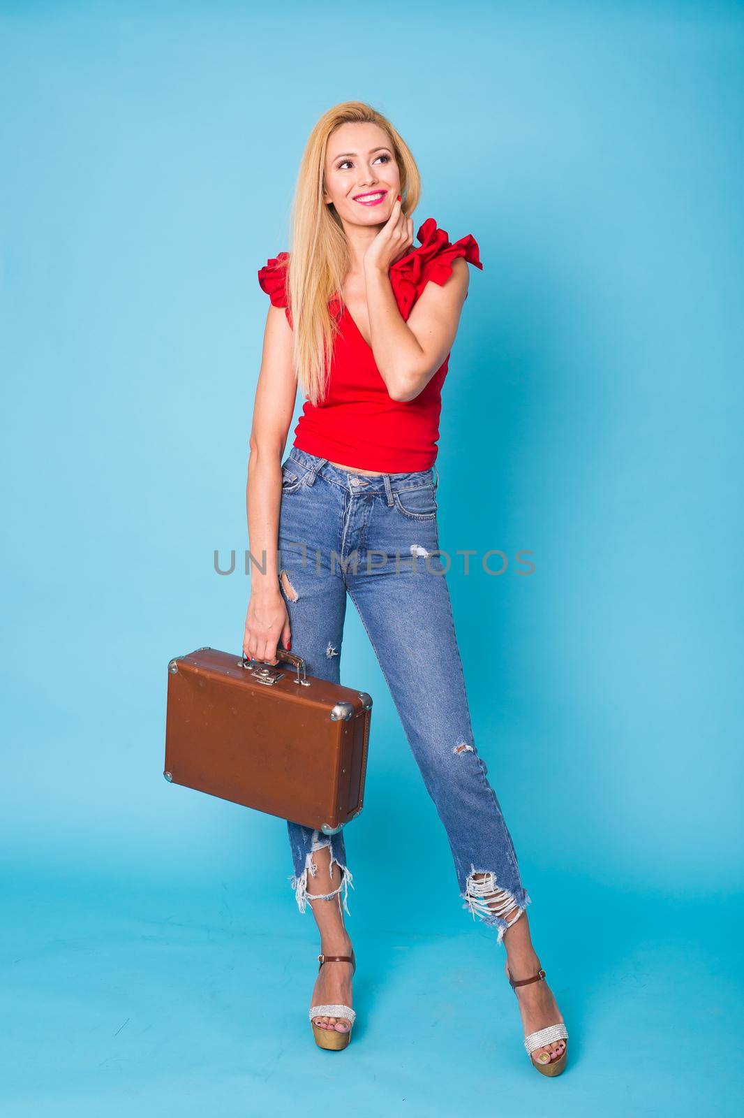 Summer, travel and vacation concept - Portrait of a beautiful young blonde woman with retro suitcase on blue background. by Satura86