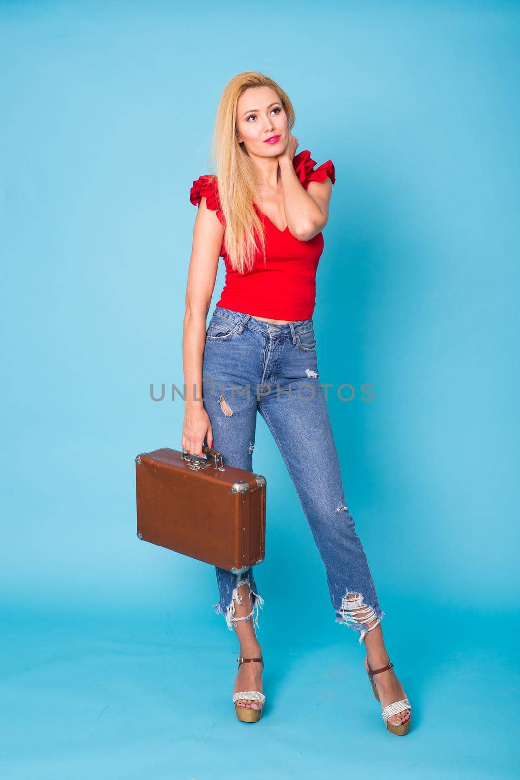 Summer, fashion and holiday concept - Beautiful blonde woman with retro suitcase on blue background by Satura86