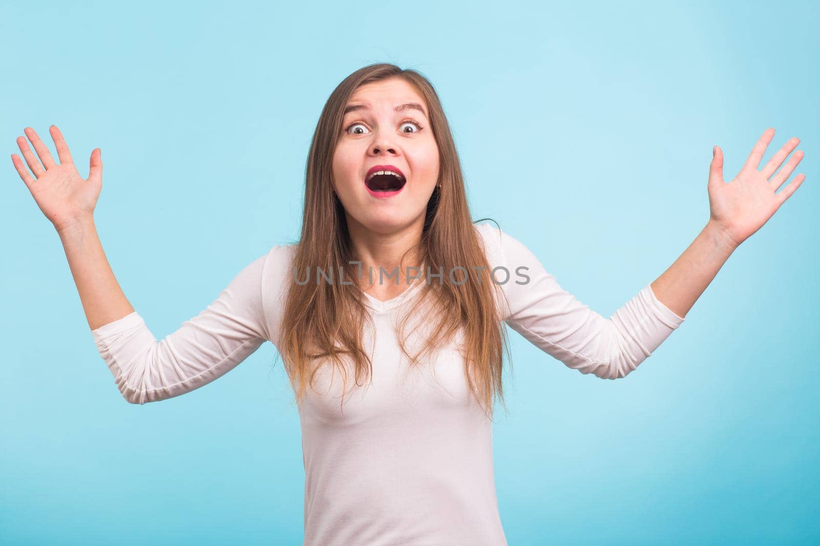 Surprised young woman shouting over blue background. Looking at camera by Satura86